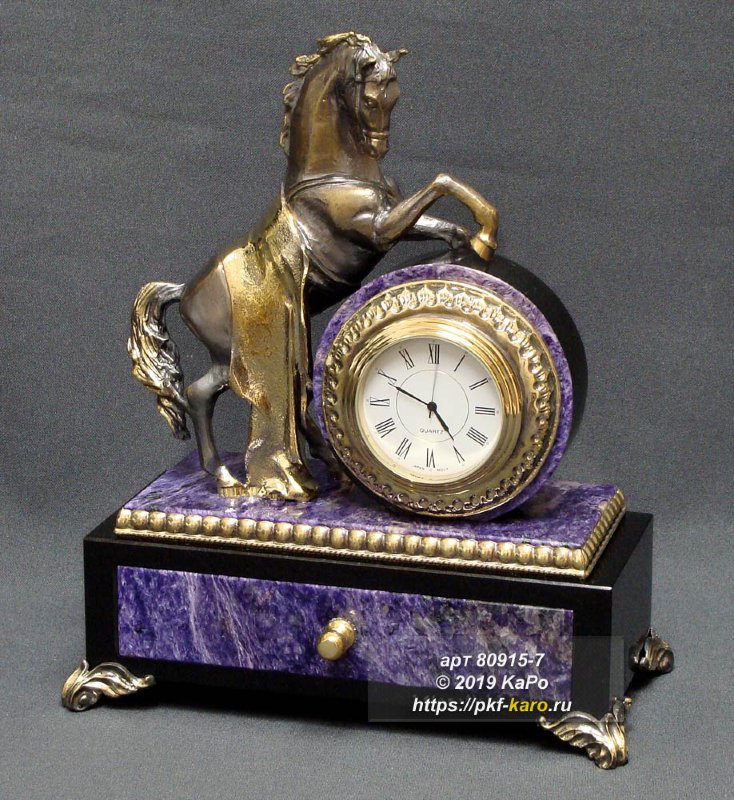Часы &quot;Конь с попоной&quot; Часы "Конь с попоной" сделаны из чароита и долерита. Встроенные кварцевые часы. Часовой механизм вынимается для смены батарейки. На фото типовое изделие, оригинал может отличаться по размеру и весу (в пределах 10%), цвету, рисунку камня. 